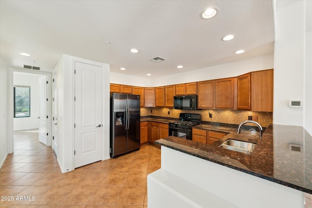 kitchen with a sink, visible vents, brown cabinets, and black appliances