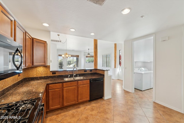 kitchen with visible vents, washer and clothes dryer, brown cabinetry, black appliances, and a sink