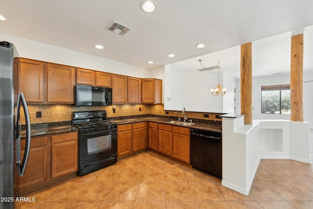 kitchen with visible vents, black appliances, decorative backsplash, and a sink