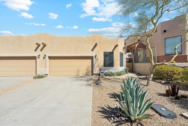 adobe home featuring stucco siding, concrete driveway, a garage, and fence