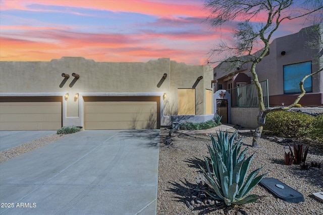 adobe home with stucco siding, an attached garage, and concrete driveway