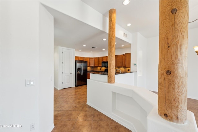 kitchen with brown cabinets, black appliances, dark countertops, recessed lighting, and light tile patterned flooring