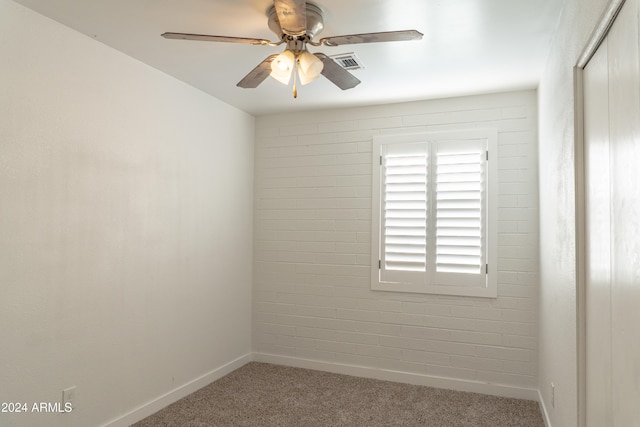 spare room with ceiling fan, brick wall, and carpet