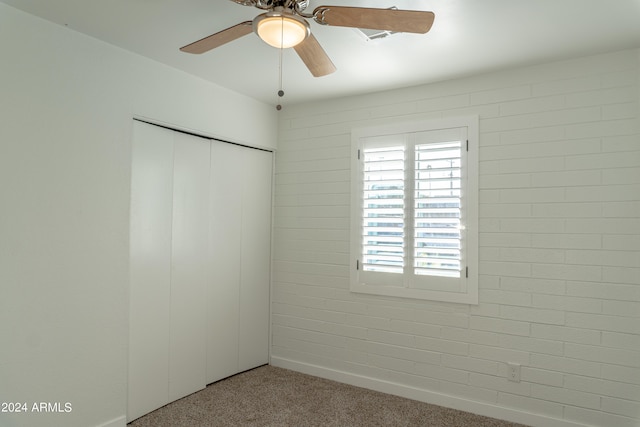 carpeted empty room with brick wall and ceiling fan