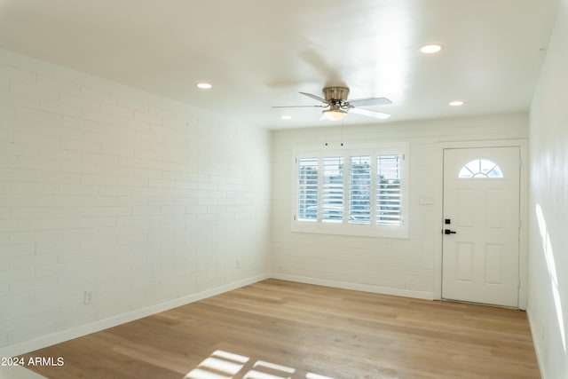 foyer with light hardwood / wood-style flooring, brick wall, and ceiling fan