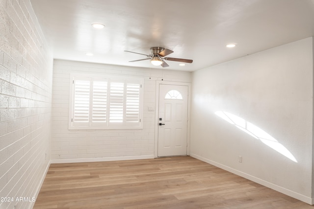 foyer featuring brick wall, light wood-type flooring, and ceiling fan