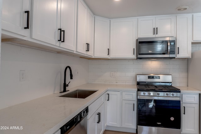 kitchen featuring white cabinetry, backsplash, appliances with stainless steel finishes, and sink