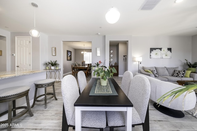 dining area featuring light hardwood / wood-style floors and an inviting chandelier