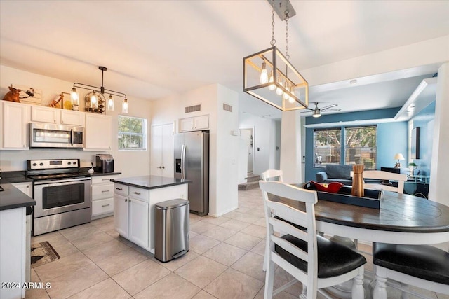 kitchen featuring appliances with stainless steel finishes, white cabinetry, plenty of natural light, and pendant lighting