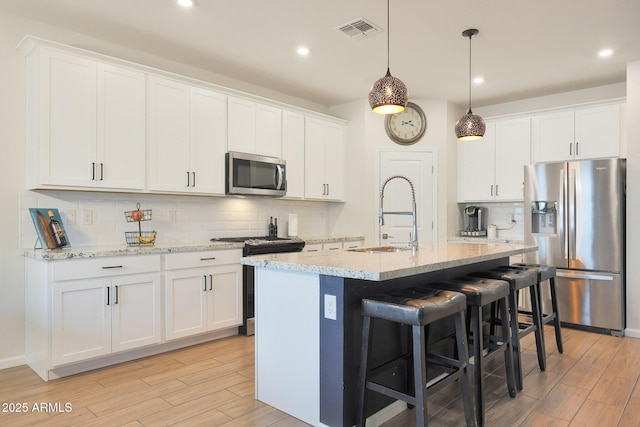 kitchen with sink, a center island with sink, white cabinets, and appliances with stainless steel finishes