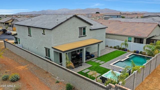 rear view of house with a fenced in pool, a mountain view, and a patio