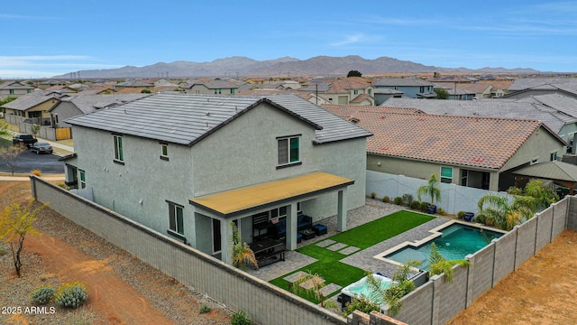 back of property with a mountain view, a fenced backyard, a residential view, and stucco siding
