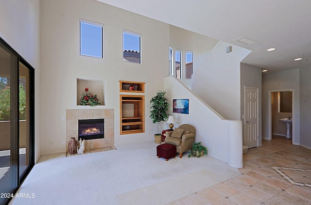 bedroom with light colored carpet, connected bathroom, multiple windows, and a tile fireplace