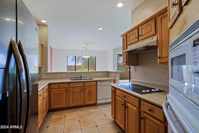 kitchen with hanging light fixtures, stainless steel fridge, dishwasher, electric cooktop, and sink