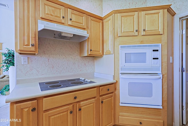 kitchen with light brown cabinetry and white appliances