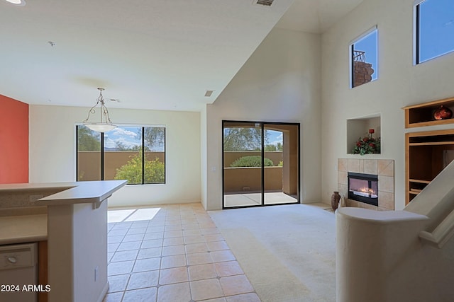 carpeted living room featuring a tile fireplace, a high ceiling, built in features, and a wealth of natural light