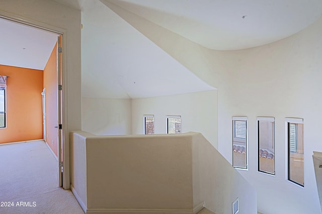 hall featuring light carpet, vaulted ceiling, and a healthy amount of sunlight