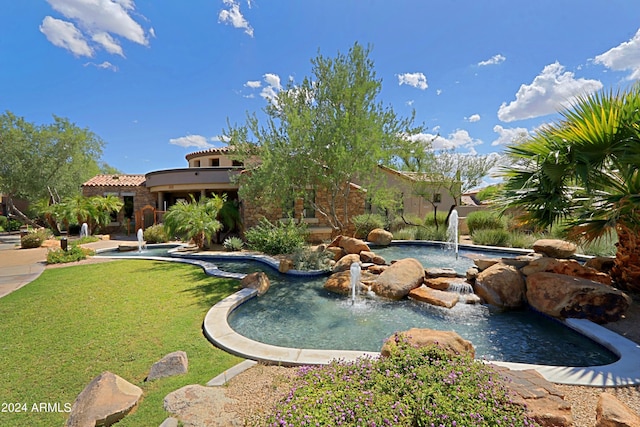 view of pool with pool water feature and a yard