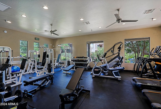 gym featuring ceiling fan, plenty of natural light, and a textured ceiling