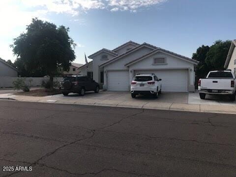 view of front facade with an attached garage, a tile roof, and driveway