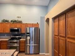 kitchen featuring visible vents, brown cabinets, appliances with stainless steel finishes, and light countertops