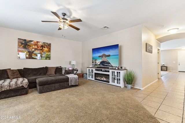 tiled living room featuring ceiling fan and a fireplace