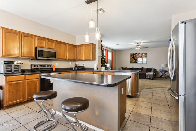 kitchen featuring ceiling fan, hanging light fixtures, sink, appliances with stainless steel finishes, and a breakfast bar