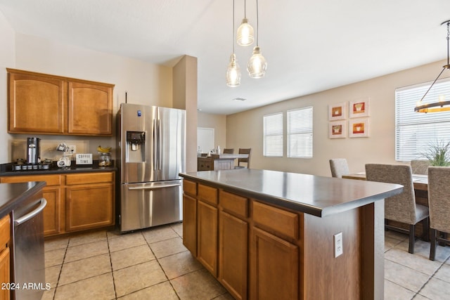 kitchen with appliances with stainless steel finishes, hanging light fixtures, a center island, and light tile patterned floors