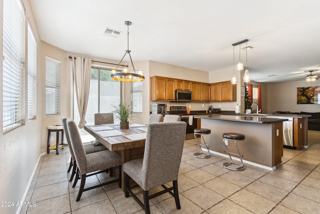 dining area with ceiling fan with notable chandelier, light tile patterned flooring, and sink