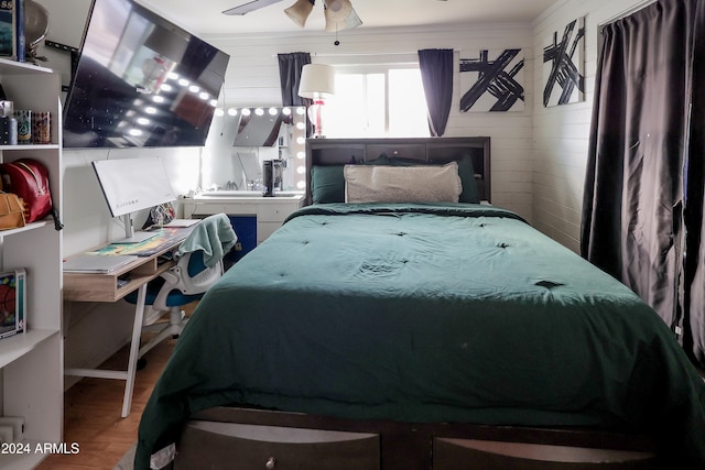 bedroom with wooden walls, wood-type flooring, and ceiling fan