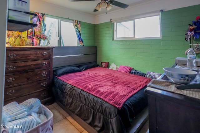 bedroom featuring ceiling fan, brick wall, light tile patterned floors, and crown molding