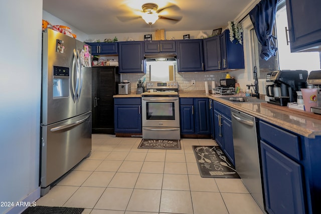 kitchen featuring light tile patterned flooring, blue cabinetry, appliances with stainless steel finishes, backsplash, and sink