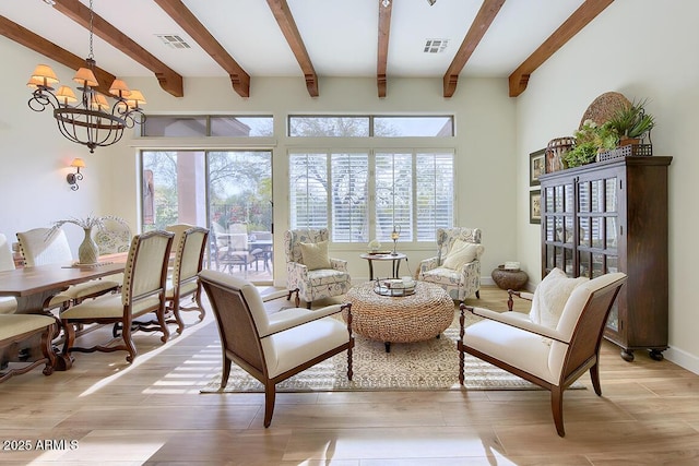 living area featuring beam ceiling, a notable chandelier, and light wood-type flooring