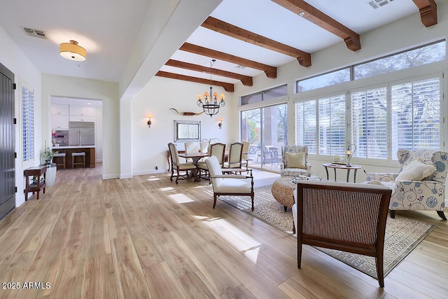 living room featuring beamed ceiling, a chandelier, and light wood-type flooring