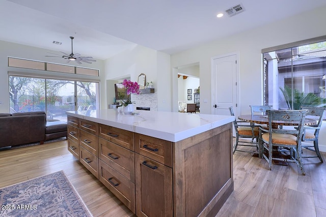 kitchen featuring ceiling fan, a kitchen island, and light hardwood / wood-style flooring