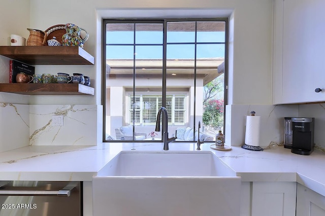 kitchen featuring white cabinetry, sink, light stone countertops, and a healthy amount of sunlight