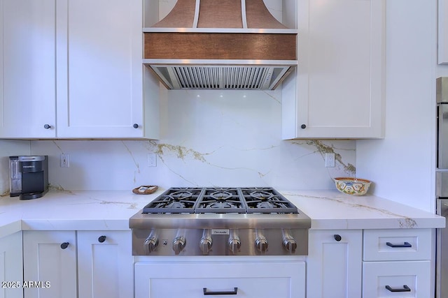 kitchen with premium range hood, stainless steel gas stovetop, tasteful backsplash, and white cabinets