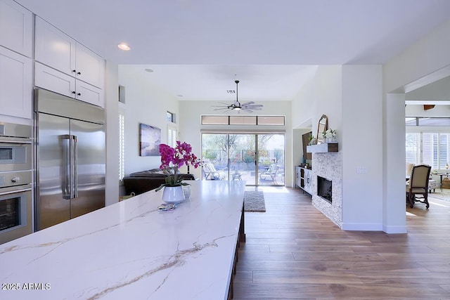 kitchen featuring white cabinetry, appliances with stainless steel finishes, light stone countertops, and a wealth of natural light