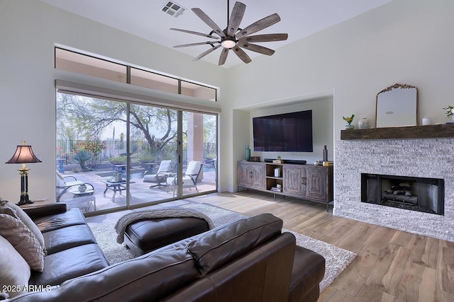 living room with ceiling fan, a fireplace, and light hardwood / wood-style floors