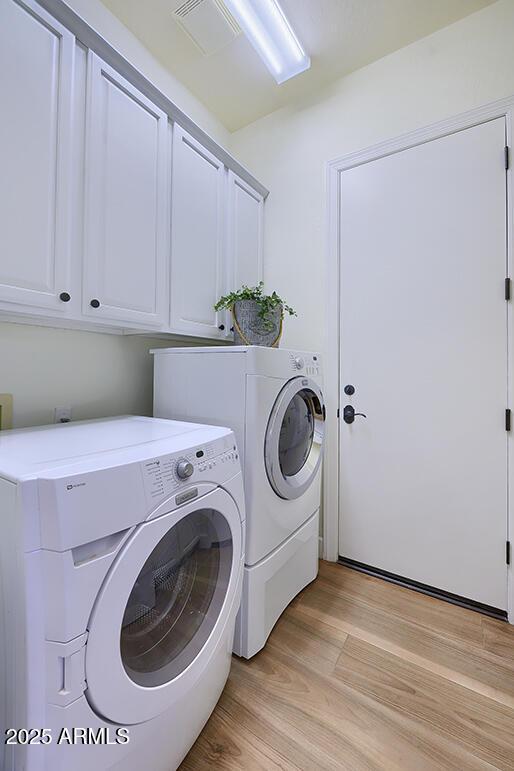 washroom with cabinets, independent washer and dryer, and light hardwood / wood-style floors