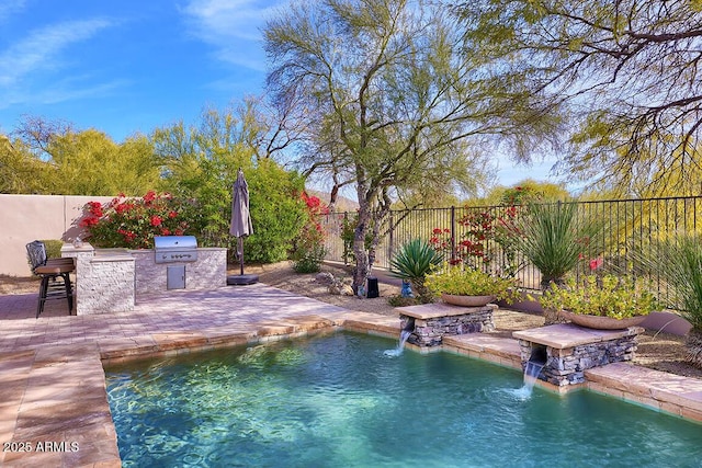 view of pool with pool water feature, a patio area, grilling area, a bar, and exterior kitchen