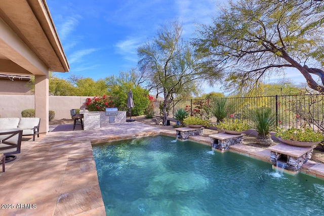 view of pool with an outdoor kitchen, area for grilling, pool water feature, and a patio area