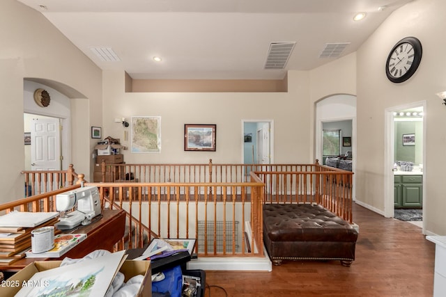 corridor featuring an upstairs landing, visible vents, arched walkways, and wood finished floors