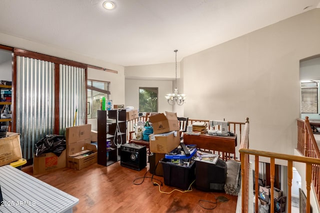 interior space with a notable chandelier, wood finished floors, and vaulted ceiling