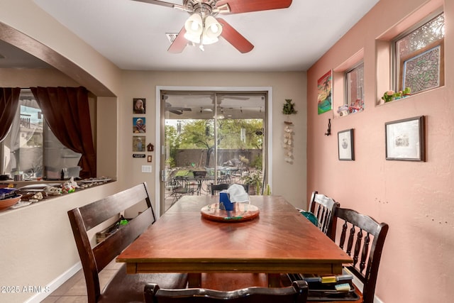 tiled dining space with arched walkways and ceiling fan