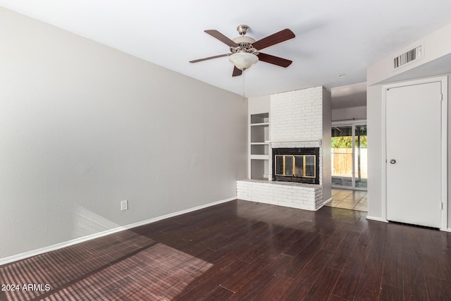 unfurnished living room featuring ceiling fan, dark hardwood / wood-style flooring, and a brick fireplace