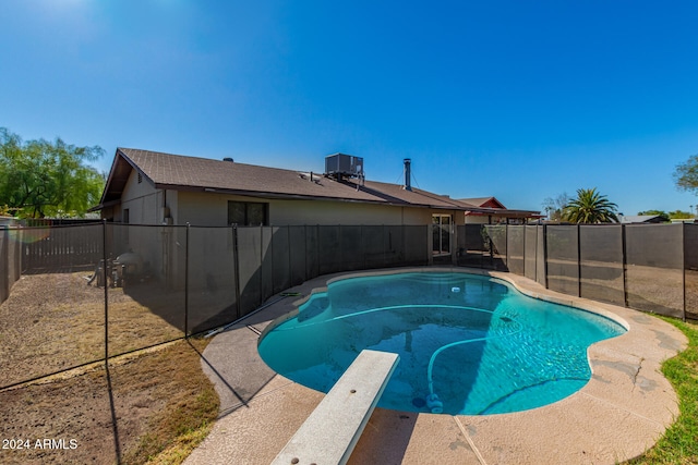 view of swimming pool featuring a diving board and central air condition unit