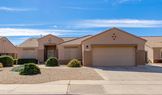 view of front of house with a garage, driveway, a tiled roof, and stucco siding