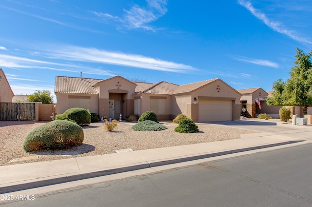 view of front of house featuring an attached garage, fence, driveway, a tiled roof, and stucco siding