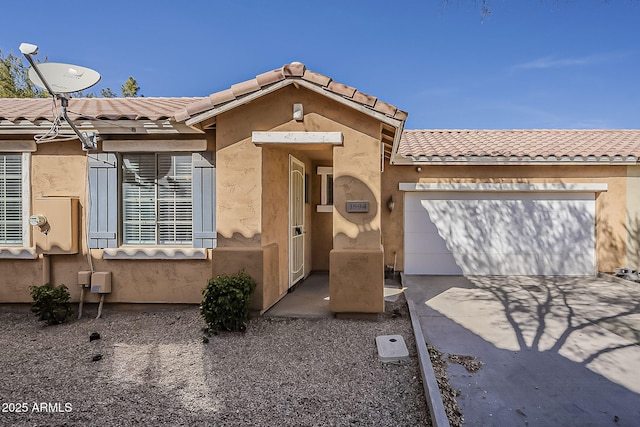 view of front of house featuring a tiled roof, an attached garage, driveway, and stucco siding